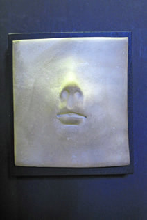 Small white pit fired ceramic face wall piece mounted on 3.5" square painted black