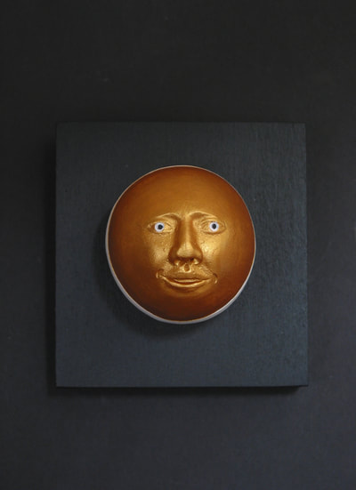 photo of ceramic wall piece round head painted gold and mounted on 3.5" black block