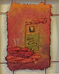 handmade paper wall piece in shades of rust with some green. Gold painted ceramic shard